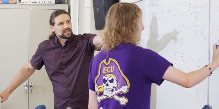 Fulbright Scholar-in-Residence Dr. Maciej Majka instructs graduate student Chris Bonham-James as he writes an equation during a Physics 4226 class.