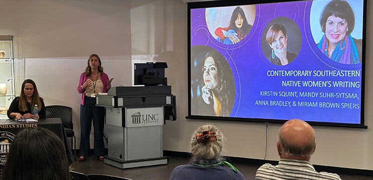 Two women next to a screen showing images of contemporary southeastern native women writers