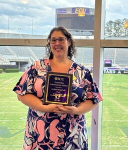 Andrea Menichelli holding her award with the ECU Pirates football stadium in the background