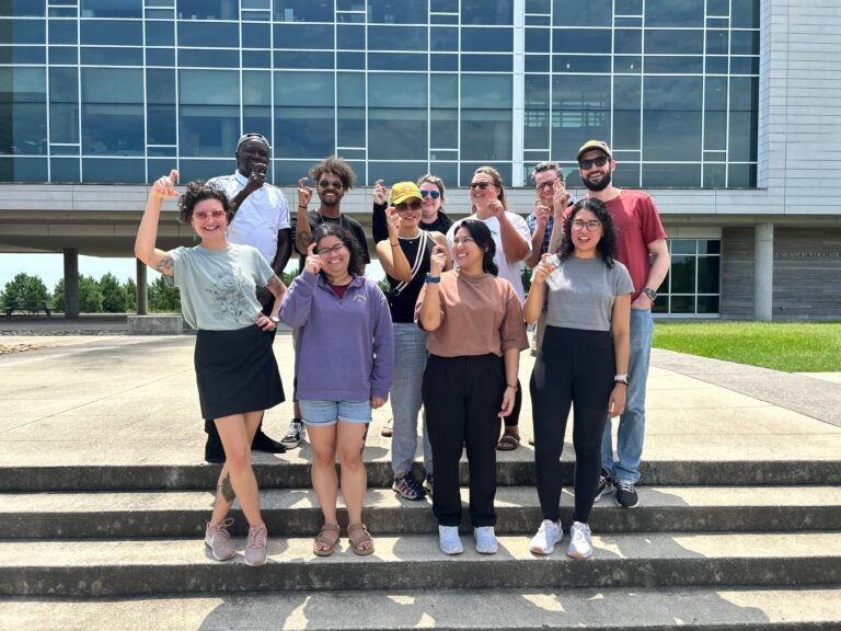 Students in front of the Coastal Studies Institute Building holding up their fingers in the Pirate hook symbol