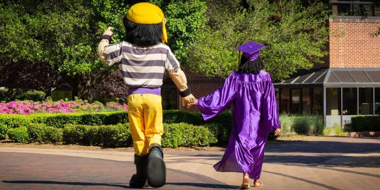 Pete holding hands and walking off with a graduate in robes